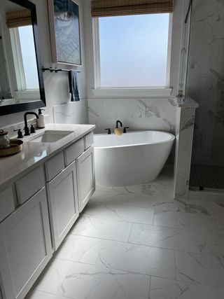A serene bathroom featuring a freestanding tub, marble tiles, a sleek vanity, and modern fixtures.