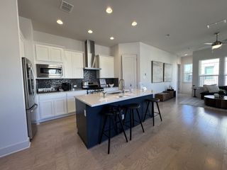 Model Home A chic modern kitchen with white cabinetry, black backsplash, and a large island with barstool seating.