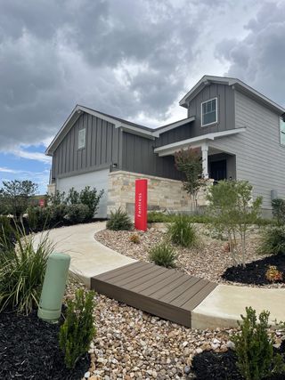 A modern gray and stone home with landscaped yard in Cinco Lakes by Centex, San Antonio, TX.