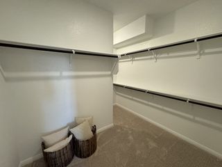 A spacious walk-in closet with ample shelving, soft carpet, and decorative baskets for storage.