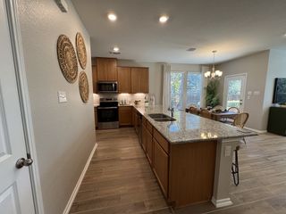 Model Home A modern kitchen with granite countertops, wooden cabinets, and a cozy dining area with natural light and warm decor.