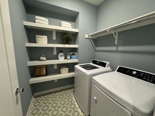 A functional laundry room with built-in shelves, a hanging rod, and soft blue walls for a refreshing, organized space.