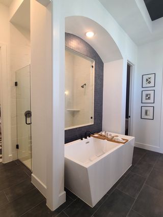 A modern bathroom featuring a sleek tub, blue accent tiles, and elegant lighting, creating a tranquil spa-like retreat.