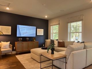 A cozy living room featuring a spacious sectional sofa, dark accent wall, and stylish decor with natural light from large windows.