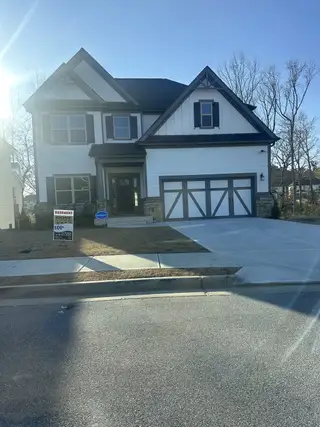 A charming two-story home with stone accents and a spacious driveway in Dove Lake by Century Communities (Grayson, GA).