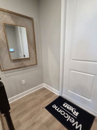 A welcoming entryway featuring a stylish mirror, sleek hardwood floors, and a welcoming mat with modern decor.