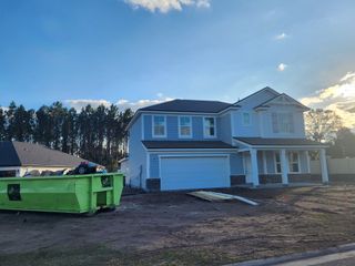 A modern two-story home under construction with a covered porch and two-car garage.