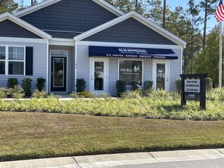 A charming model home in Pine Hills at Cane Bay by D.R. Horton, featuring a manicured lawn in Summerville, SC.