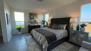 A cozy and stylish master bedroom with large windows, modern furnishings, and a relaxing ambiance.