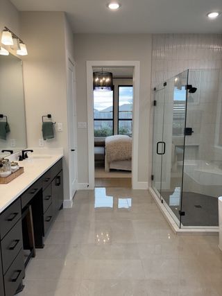A sleek bathroom featuring a glass shower, elegant vanity, and neutral floor tiles for a modern touch.