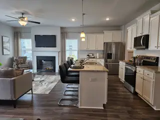 Modern open-concept living area with sleek kitchen, granite island, cozy seating, and a fireplace.