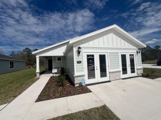 A charming model home in Kings Preserve (Jacksonville, FL) by Meritage Homes features a light gray exterior with white trim and a welcoming entryway.