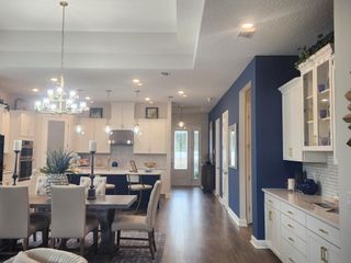 Model Home A spacious, elegant kitchen and dining area with white cabinetry, blue accent wall, and modern chandeliers.
