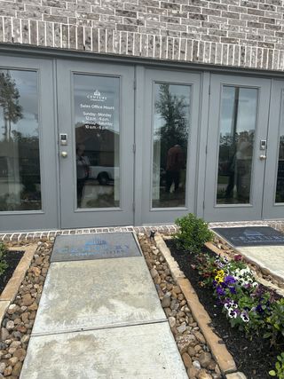 Street view Elegant office entrance with gray double doors and vibrant flowerbeds in Lakes at Black Oak by Century Communities (Magnolia, TX).