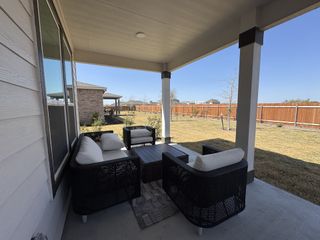 A cozy patio with wicker seating and a spacious fenced yard, perfect for relaxation and outdoor enjoyment.