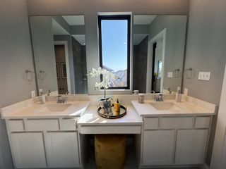 Elegant bathroom with dual sinks, marble countertops, and a large window accentuating natural light.