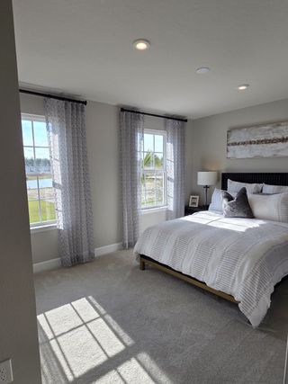 A cozy bedroom with large windows, sheer curtains, and modern decor offering serene views.