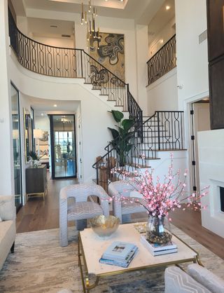 A luxurious living room with a grand staircase, modern art, elegant furniture, and chic lighting fixtures.