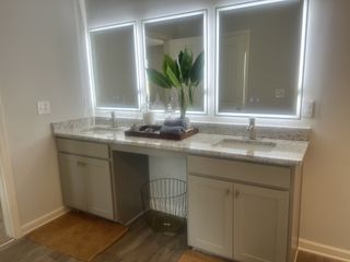 A modern bathroom with dual sinks, illuminated mirrors, and elegant granite countertops for a stylish touch.