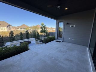 A covered patio with sleek concrete flooring, overlooking a landscaped yard with modern fencing and greenery.