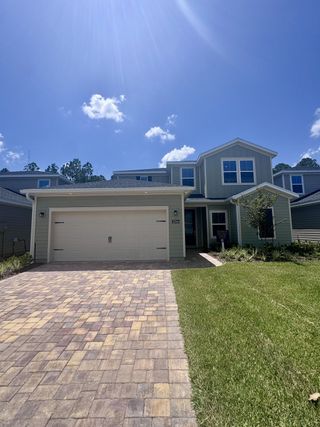 A modern two-story home with a paved driveway and manicured lawn in Russell Retreat by Lennar (Green Cove Springs, FL).