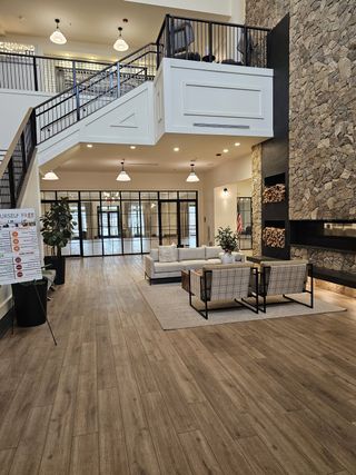 A spacious clubhouse lounge with a stone fireplace, contemporary seating, and an open mezzanine for social gatherings.