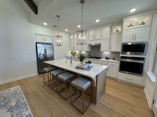 A bright and airy kitchen with white cabinetry, gold hardware, and a large quartz island, blending modern and classic elegance.