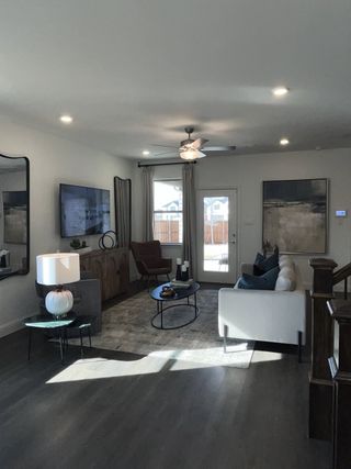 A modern living room featuring a sleek ceiling fan, comfortable seating, and elegant decor with a bright ambiance.