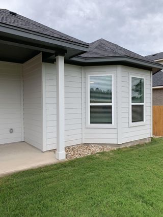 A charming new home exterior with white siding and manicured lawn in Cedar Brook by M/I Homes (Leander, TX).
