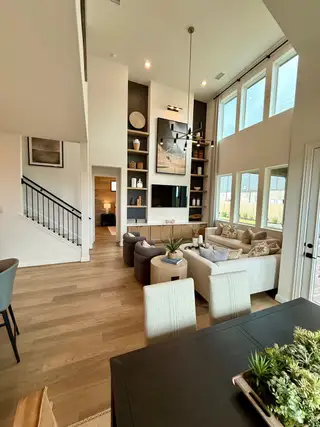 A modern living area with high ceilings, large windows, elegant shelving, and stylish decor, exuding spacious charm.