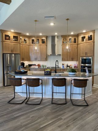 A stylish kitchen with warm wood cabinetry, a large island, modern pendant lights, and high-end finishes.