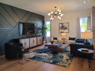 A modern living room with geometric accent wall, chic chandelier, cozy seating, and abstract art. Perfect for entertaining.