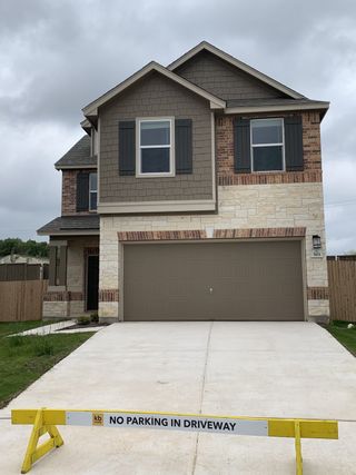 Street view A modern two-story home with a stone and brick facade in Village at Northtown by KB Home (Pflugerville, TX).