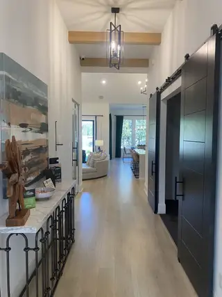 A modern hallway with sleek barn doors, elegant lighting, and chic decor, leading to a cozy living area.