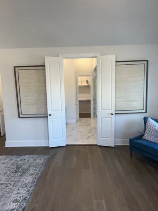A cozy room with elegant double doors, wood flooring, and a patterned rug, leading to a stylish, tile-floored space.