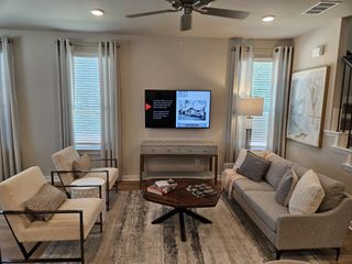A cozy living room with neutral tones, modern furnishings, and a wall-mounted TV, creating a welcoming atmosphere.