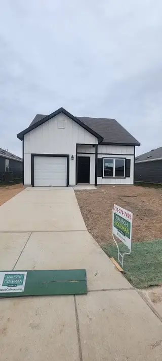 A modern white home with black accents and a pristine driveway in Red Hawk Landing by Rausch Coleman Homes (San Antonio, TX).