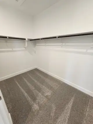 A spacious walk-in closet with plush carpeting, sleek shelving, and ample storage space.