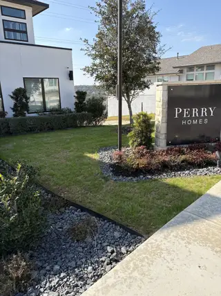 Model Home A sleek, contemporary exterior with sharp rooflines, large windows, and manicured landscaping in Esperanza by Perry Homes (Boerne, TX).