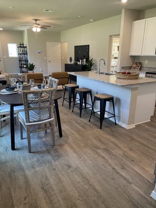 A modern open-concept kitchen and dining area with sleek barstools, wood flooring, and neutral tones.