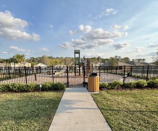 A fenced playground and community space with lush landscaping in Concorde by D.R. Horton (Sanford, FL).