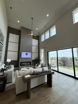 A spacious living room with high ceilings, modern fireplace, and large windows opening to a scenic patio.