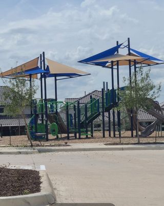 A vibrant playground with sun shades in The Grove Frisco - 40' Lots by Shaddock Homes (Frisco, TX).