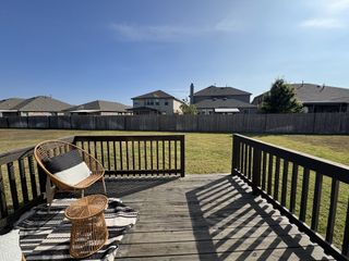 Model Home A serene backyard deck with a cozy wicker chair, perfect for relaxing under the clear blue sky.