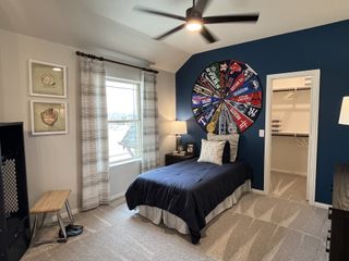 A vibrant bedroom with a blue accent wall, sports team decor, and a walk-in closet.