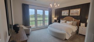 Model Home A luxurious master bedroom with a statement wood accent wall, elegant lighting, and large windows overlooking the backyard.