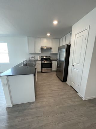 A modern kitchen with sleek cabinetry, stainless steel appliances, and laminate flooring.