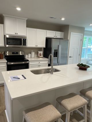 A modern kitchen with sleek white cabinets, stainless steel appliances, and a spacious island with seating.