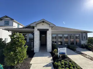 Street view A beautiful stone-accented home with lush landscaping in Waterstone Crossing by Meritage Homes (Kyle, TX).