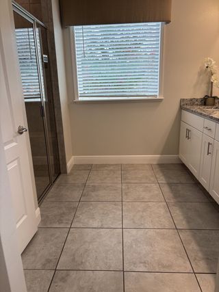 A sleek bathroom with tiled floors, granite countertop, and elegant shower enclosure.